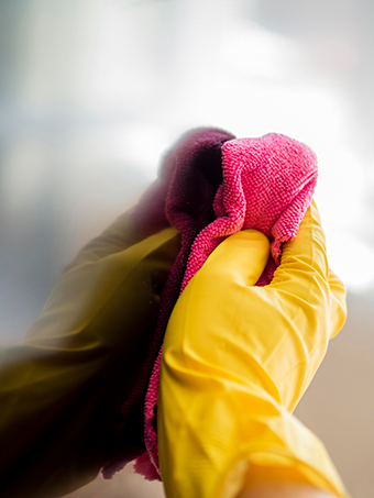 Gloved hand using microfiber cloth to wipe a screen